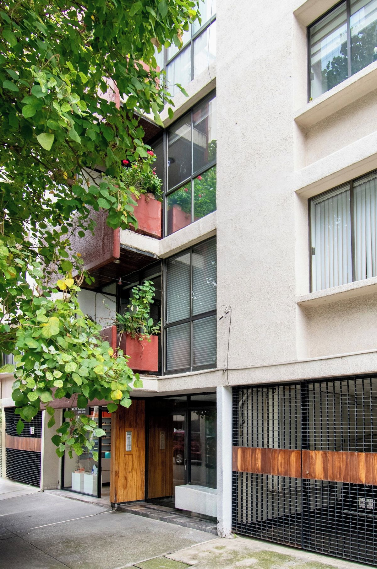 A multi-story building with a ground-level entrance, a wooden door, and a metal gate.