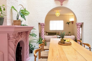 A dining area with a wooden table, chairs, and a central archway. - Casa Raíz| A Place to Belong, Rooted in Connection (Mexico City)