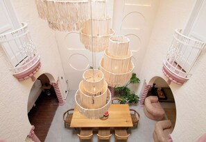 A multi-level bamboo chandelier with a central light source, surrounded by a white wall with decorative cutouts. - Casa Raíz| A Place to Belong, Rooted in Connection (Mexico City)