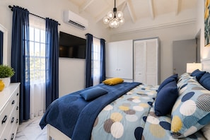Une chambre à coucher comprenant un lit, des rideaux, un appareil de climatisation, une armoire et un luminaire au plafond.