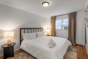 Ein Hotelzimmer mit Bett, Nachttischlampe, einem Fenster mit Vorhängen und Deckenleuchte.