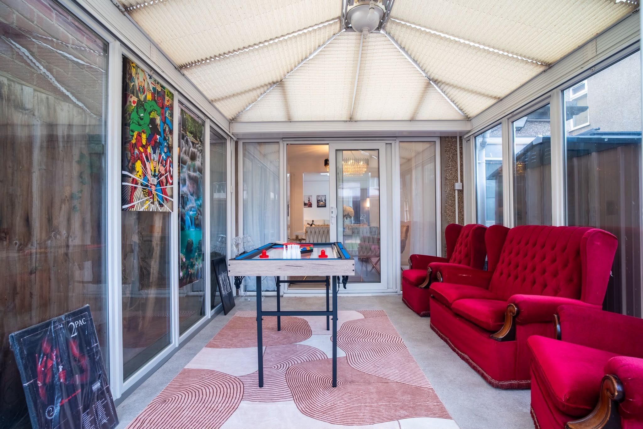 Une véranda équipée d’une table de billard, de canapés rouges et d’une grande fenêtre ornée d’œuvres d’art.