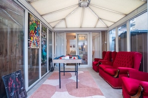 A conservatory with a pool table, red sofas, and a large window with artwork.