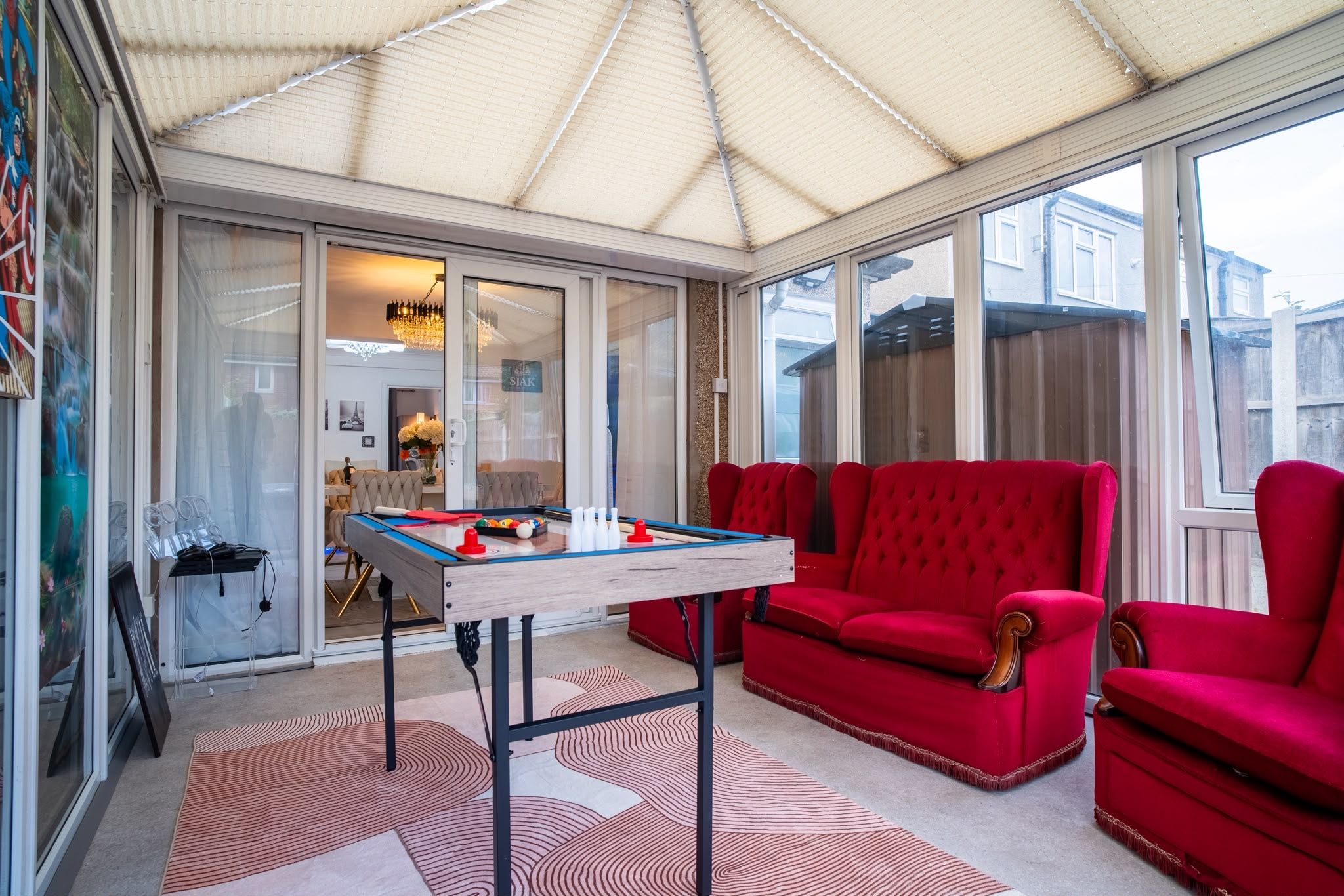A conservatory with a foosball table, red sofas, and a billiards table.