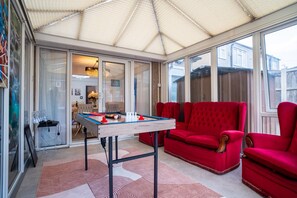Un invernadero con mesa de futbolín, sofás rojos y mesa de billar.