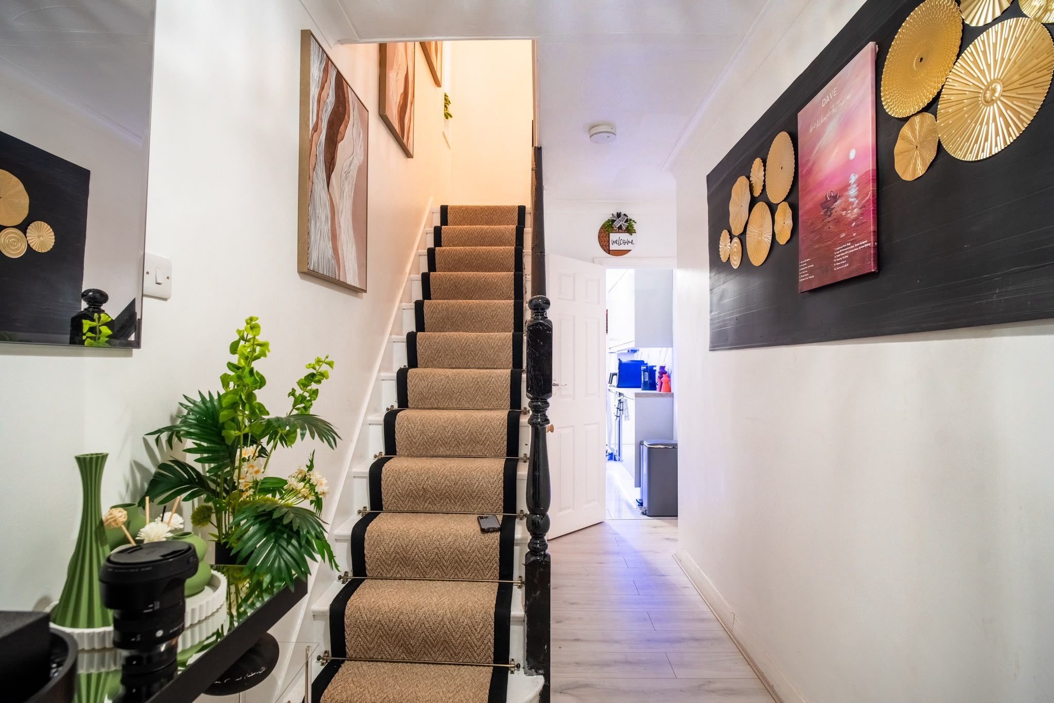 A staircase with a beige carpet and black balusters leading to a landing.