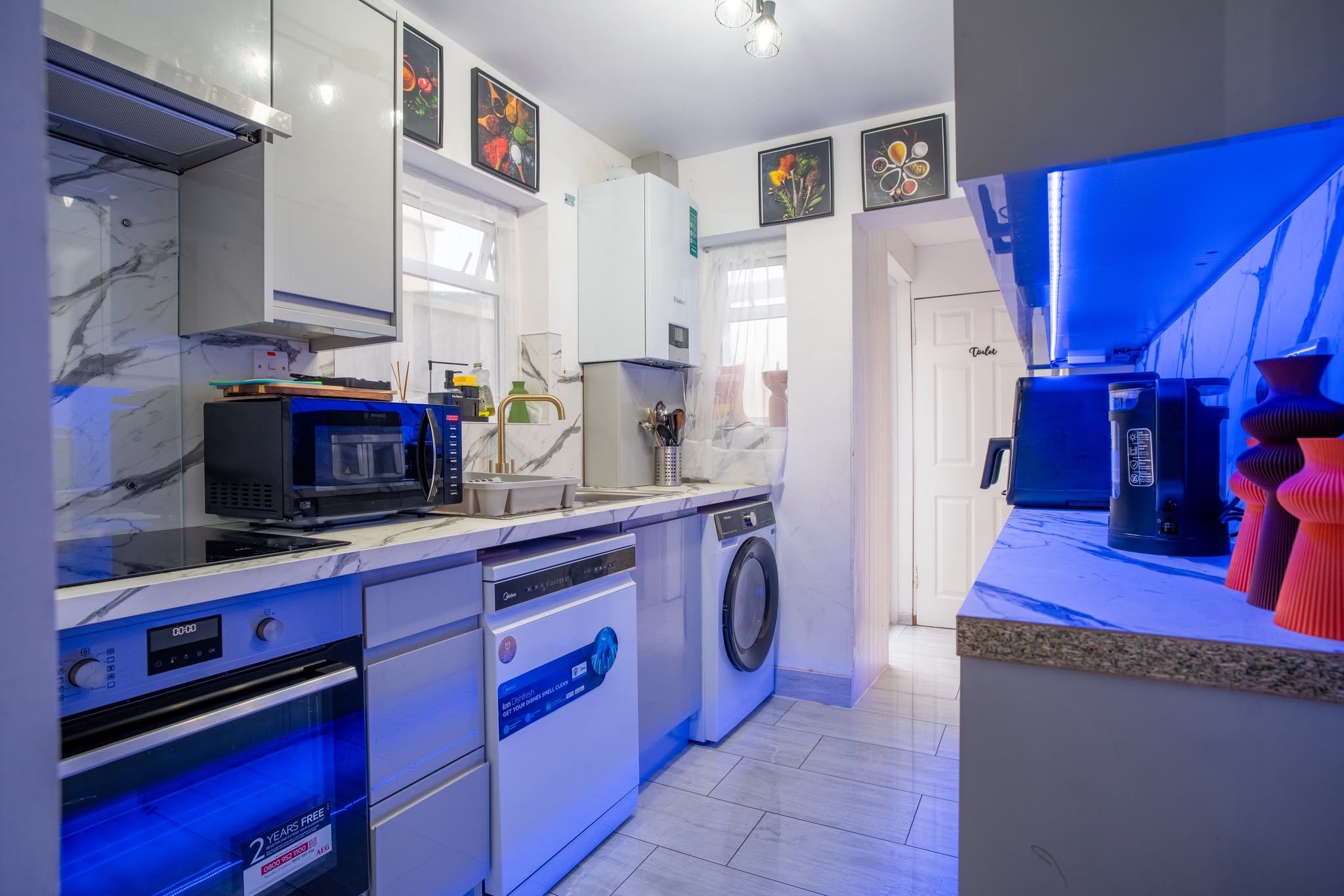 A modern kitchen with a microwave, oven, dishwasher, and washing machine.