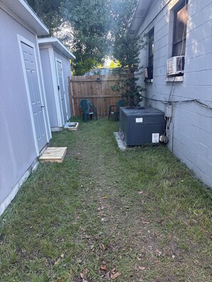 A backyard with a wooden deck, a metal heater, and a fenced area.
