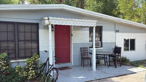En liten, envåningsbyggnad med en röd dörr och en inglasad veranda.