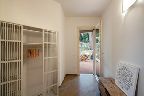 A hallway with a white closet, a wooden bench, and a door leading to an outdoor patio area. - Villa Tigli: A 5-Minute Walk From the Beach by Top Villas Sardinia (Quartu Sant'Elena)