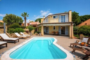 Een twee verdiepingen tellend huis met een zwembad, tuinmeubilair en een tuin.