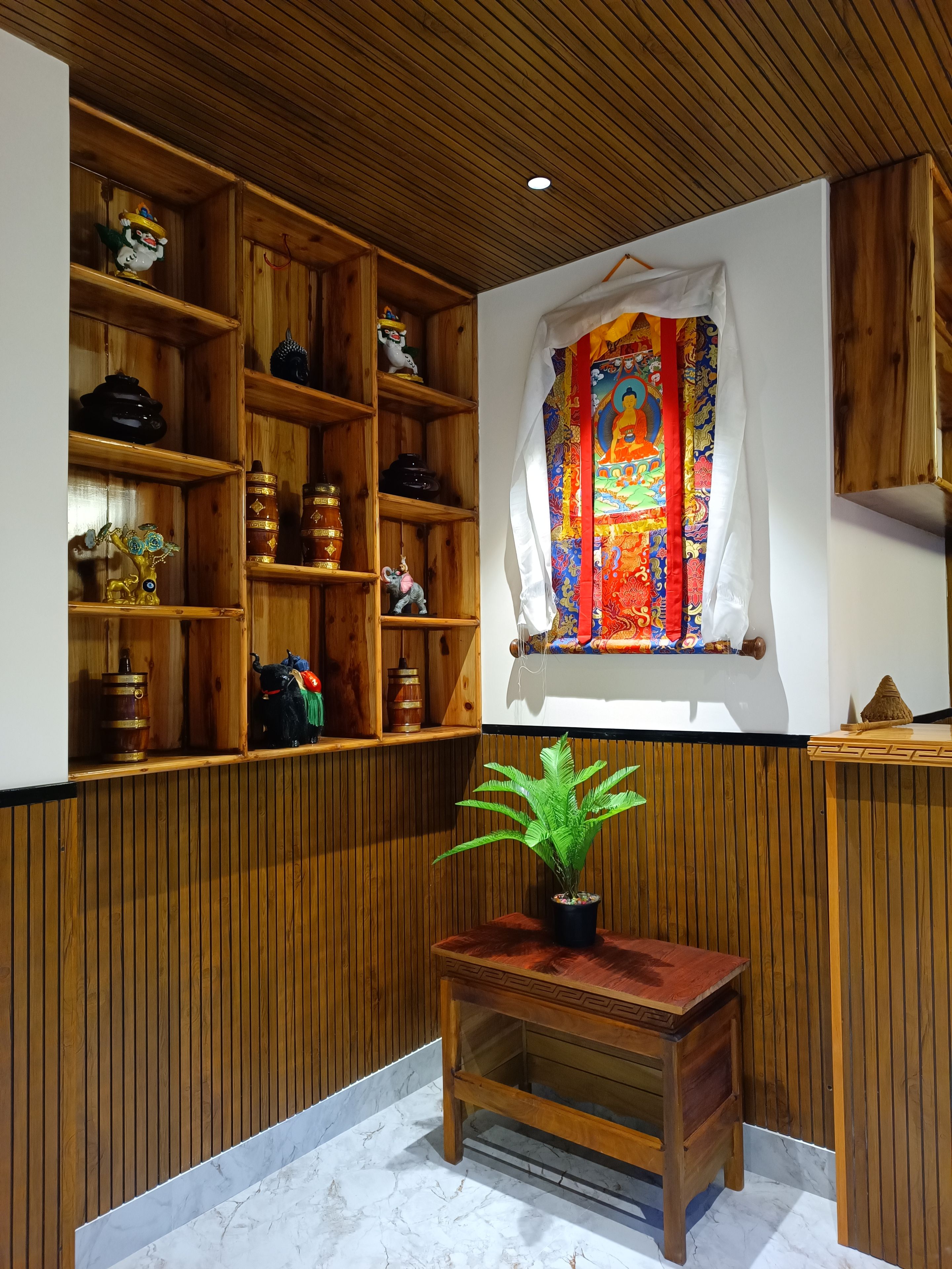 Una habitación con estanterías de madera, un ventanal con un tapiz colorido y una pequeña mesa de madera con una planta.