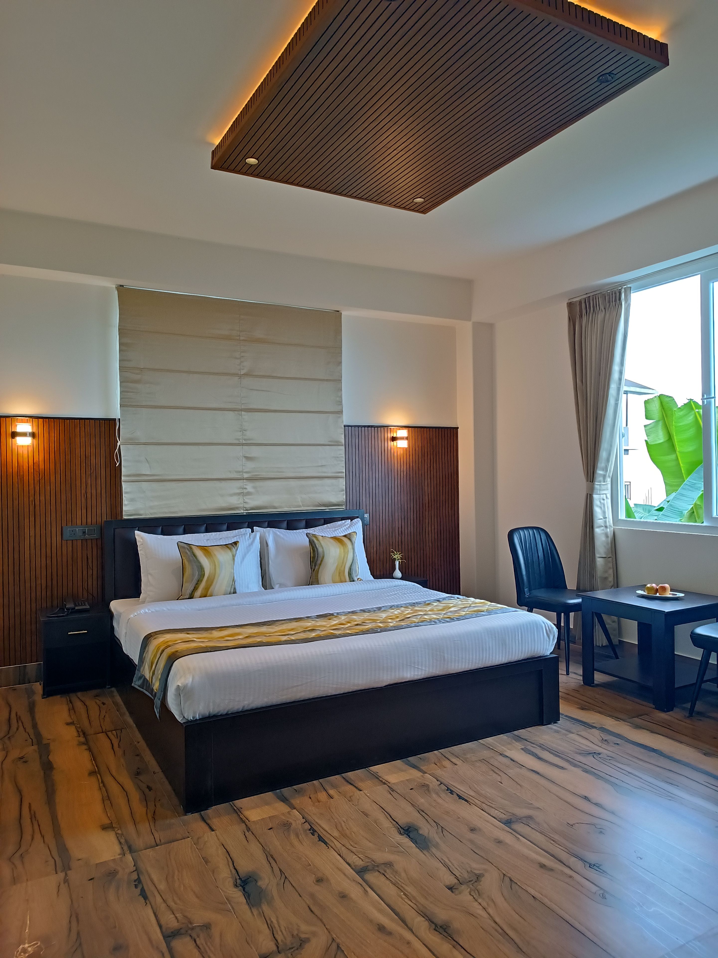 Une chambre d’hôtel moderne avec un grand lit, des tables de chevet, un bureau et une fenêtre avec des rideaux.
