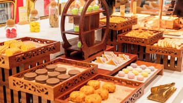 A variety of food items displayed in wooden crates and a central wooden stand with multiple glasses of beverages.