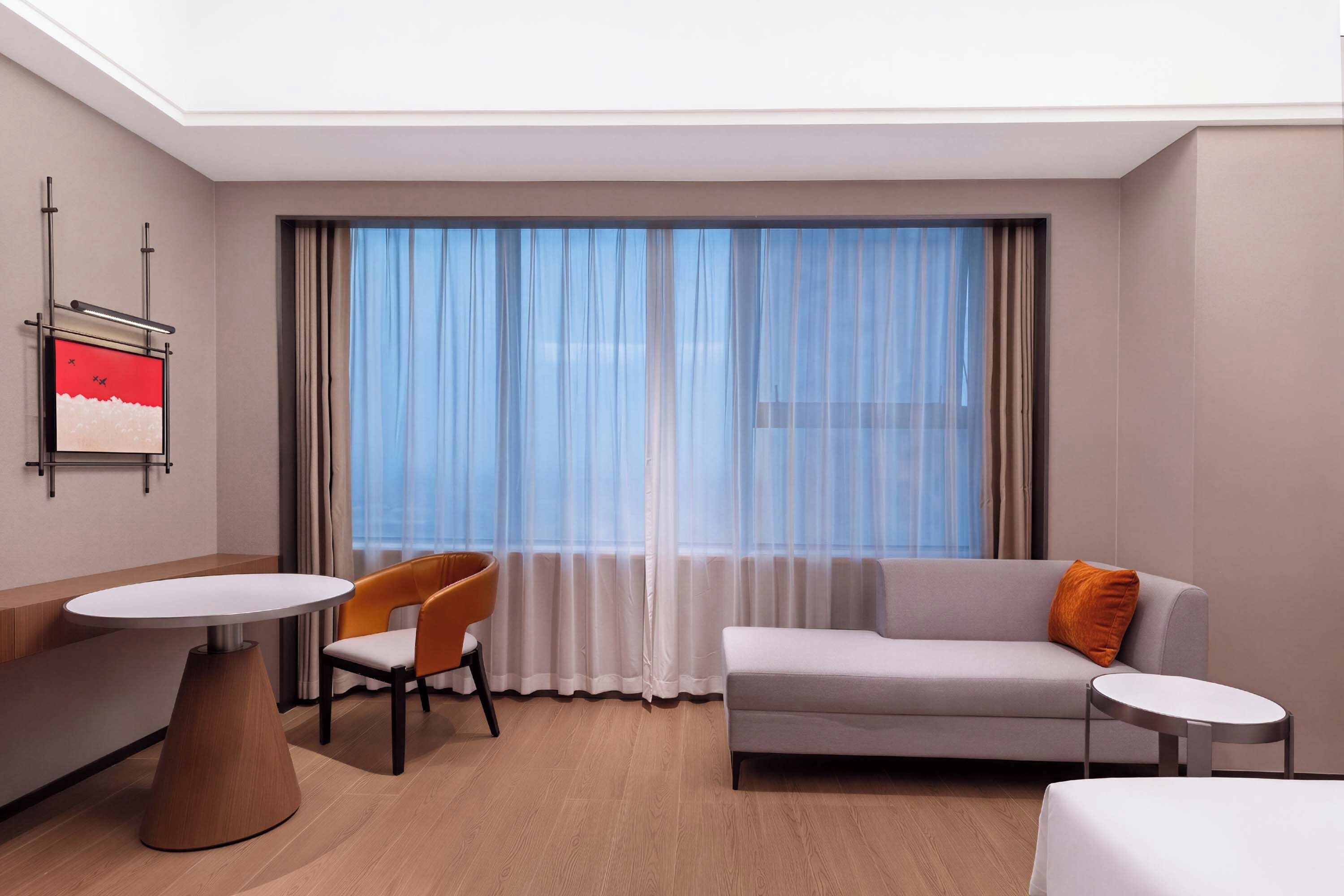 Una habitación de hotel con cama, sofá, mesa de comedor y una silla.