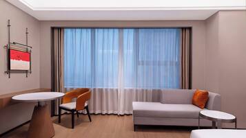 Una habitación de hotel con cama, sofá, mesa de comedor y una silla.