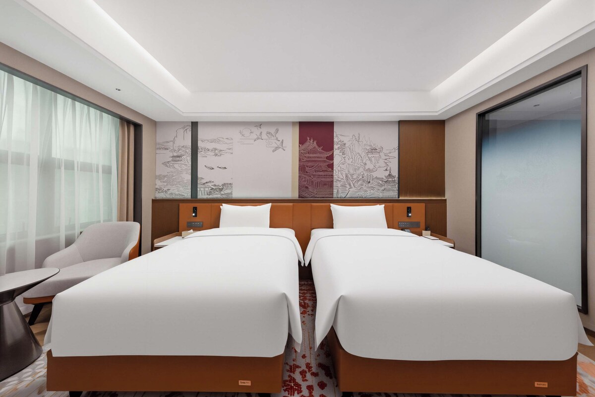 Une chambre d’hôtel avec deux lits, un bureau et une chaise.