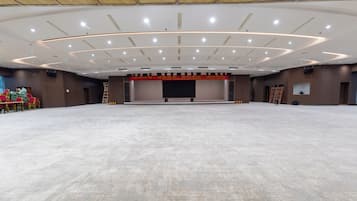 A large, empty conference room with a stage, rows of chairs, and a podium.
