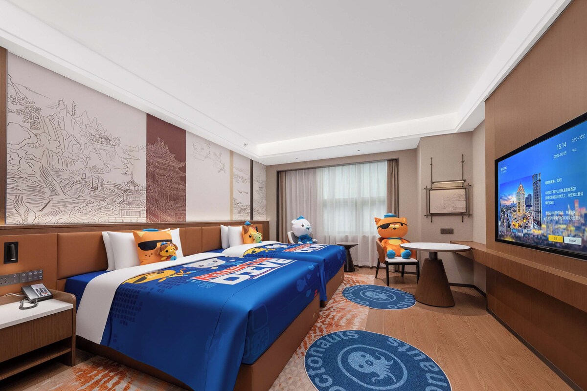 Une chambre d’hôtel avec deux lits, une télévision, un bureau et une chaise.
