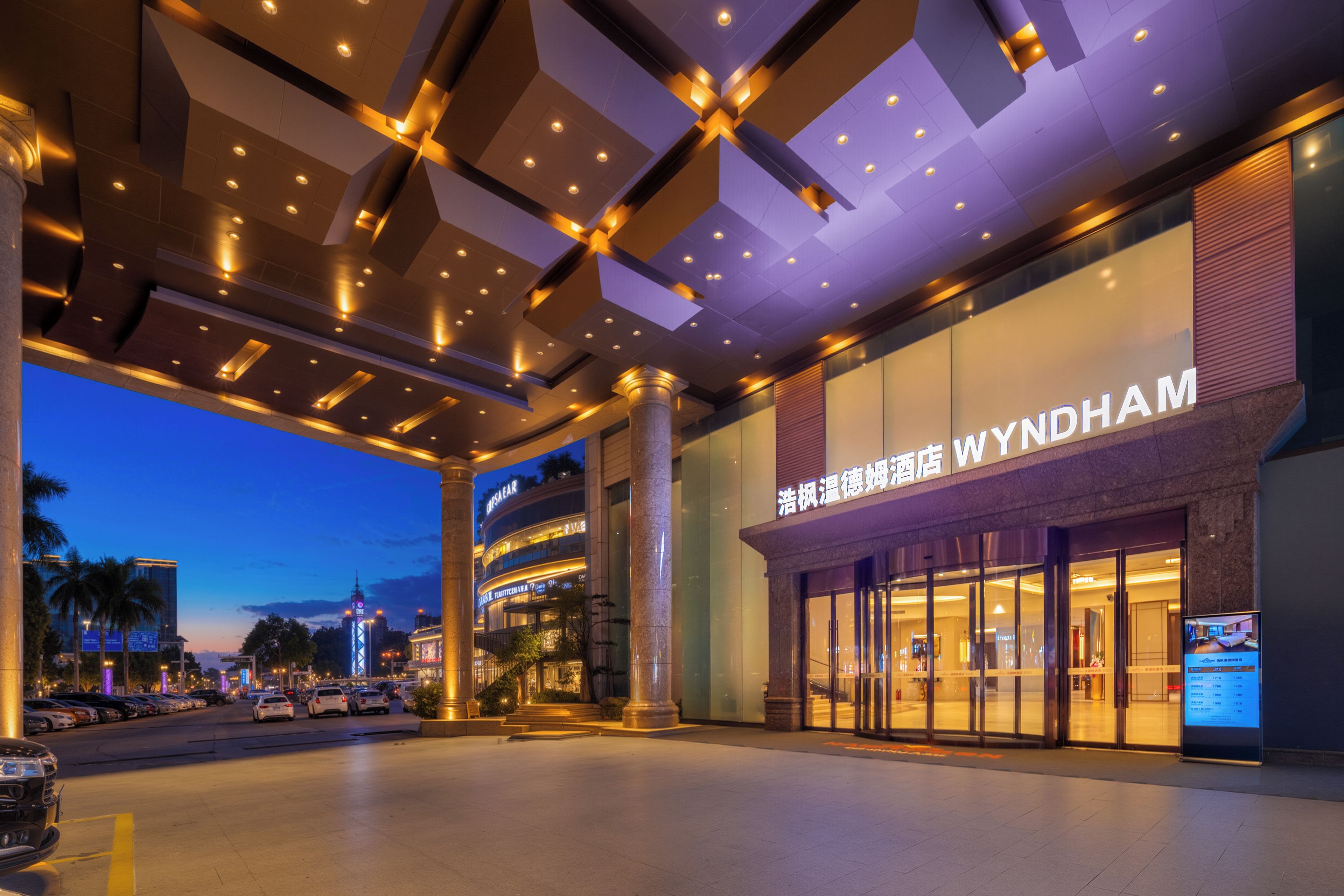 A hotel entrance with a modern design, featuring a large sign for Wyndham and a well-lit facade.