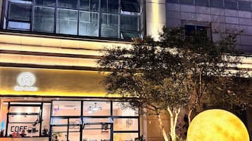 A coffee shop with outdoor seating and a large illuminated moon sculpture.
