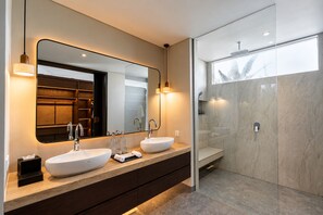 Een moderne badkamer met twee wastafels, een grote spiegel en een douche met glazen wanden.