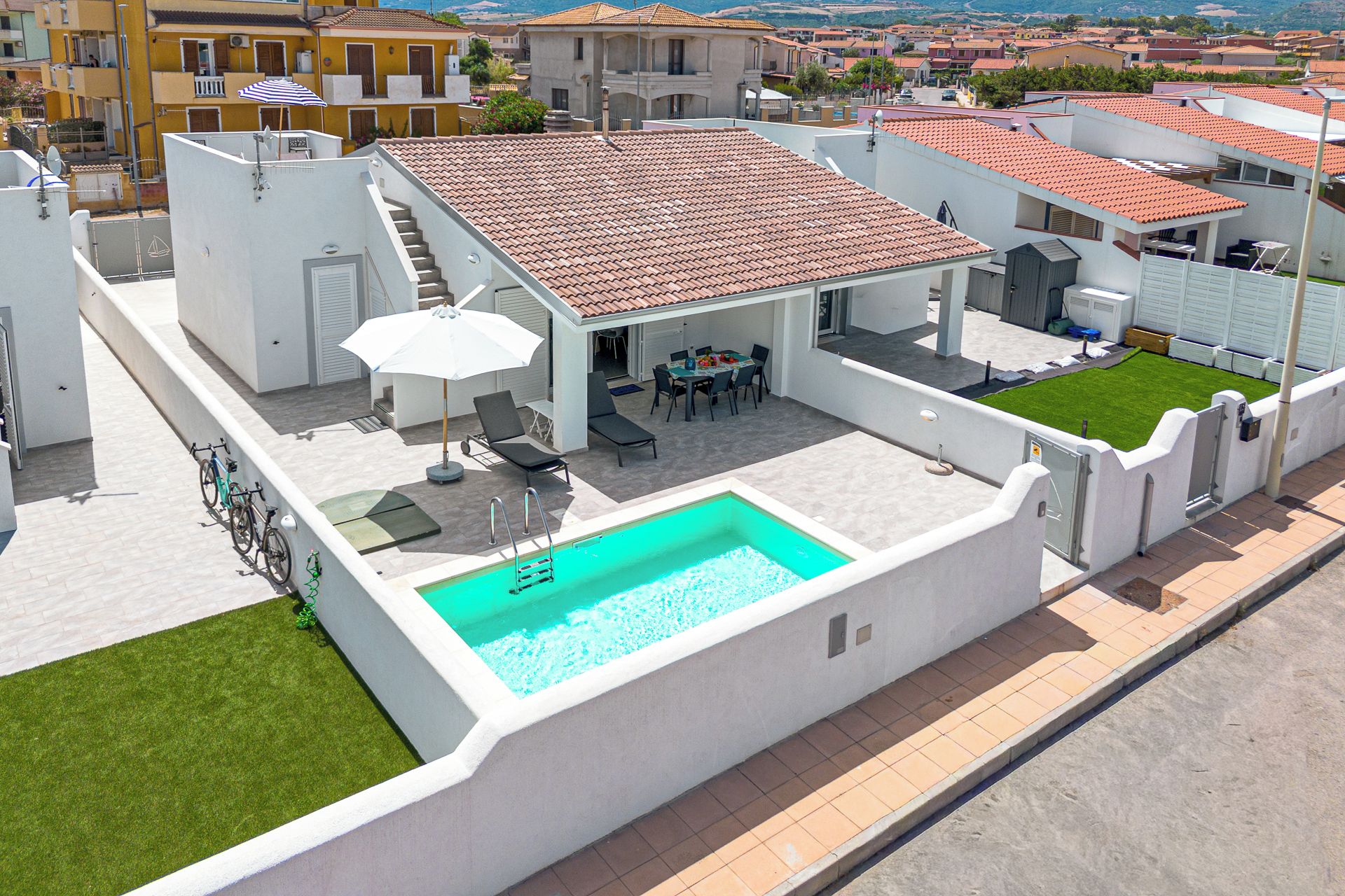 A rooftop pool area with a swimming pool, lounge chairs, and a table with chairs.