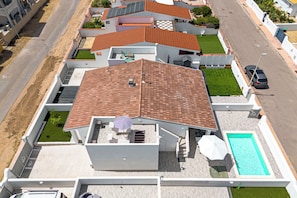 Um edifício residencial com telhado ladrilhado, piscina e uma pequena área de pátio.