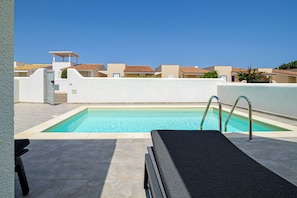 Piscina no terraço com espreguiçadeira e área coberta.