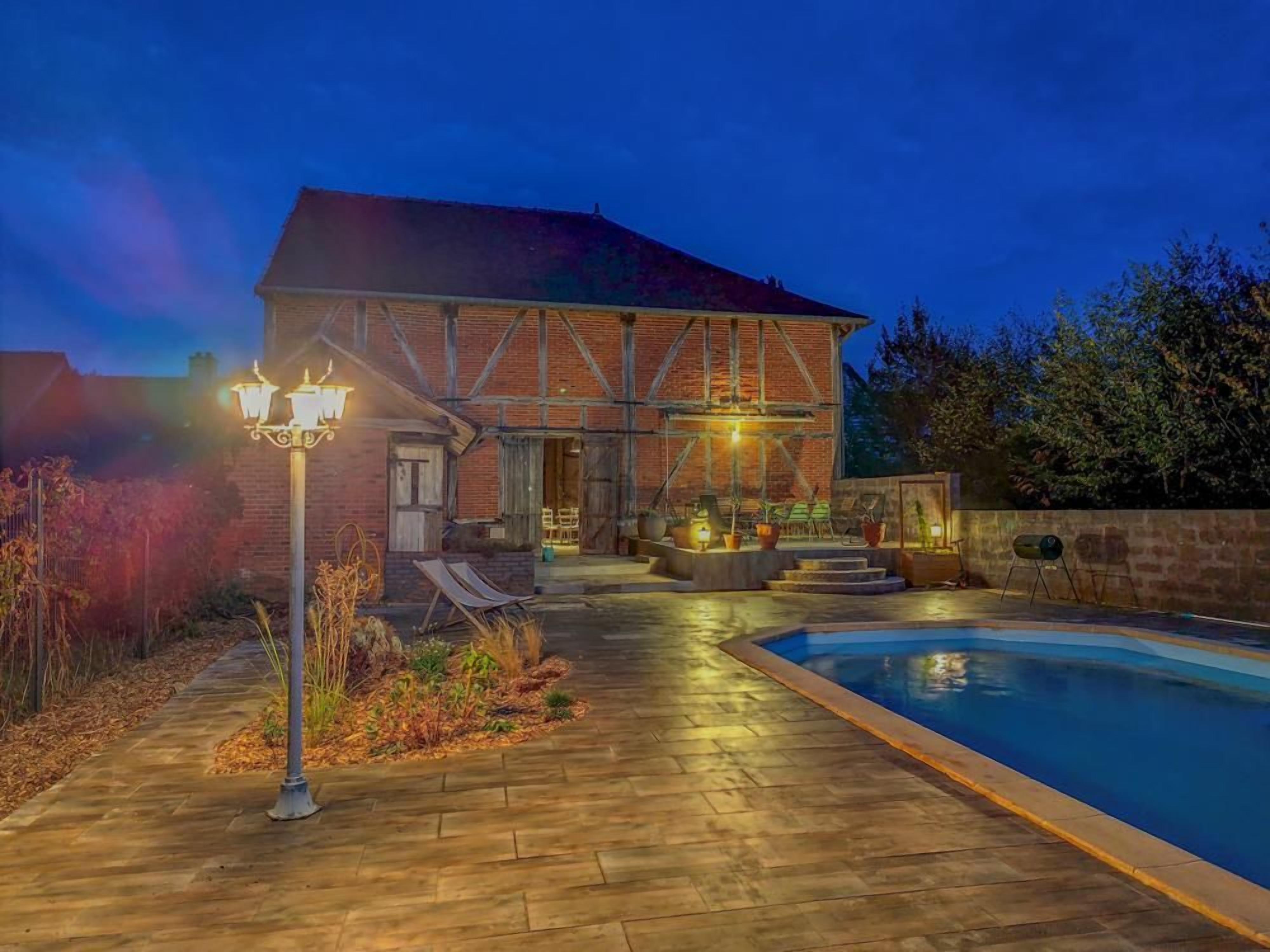 A building with a pool, outdoor lighting, and a patio area.
