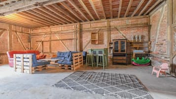 Una habitación rústica con paredes de ladrillo visto, vigas de madera, un sofá, una mesa baja, un tapete y una pequeña mesa con sillas.