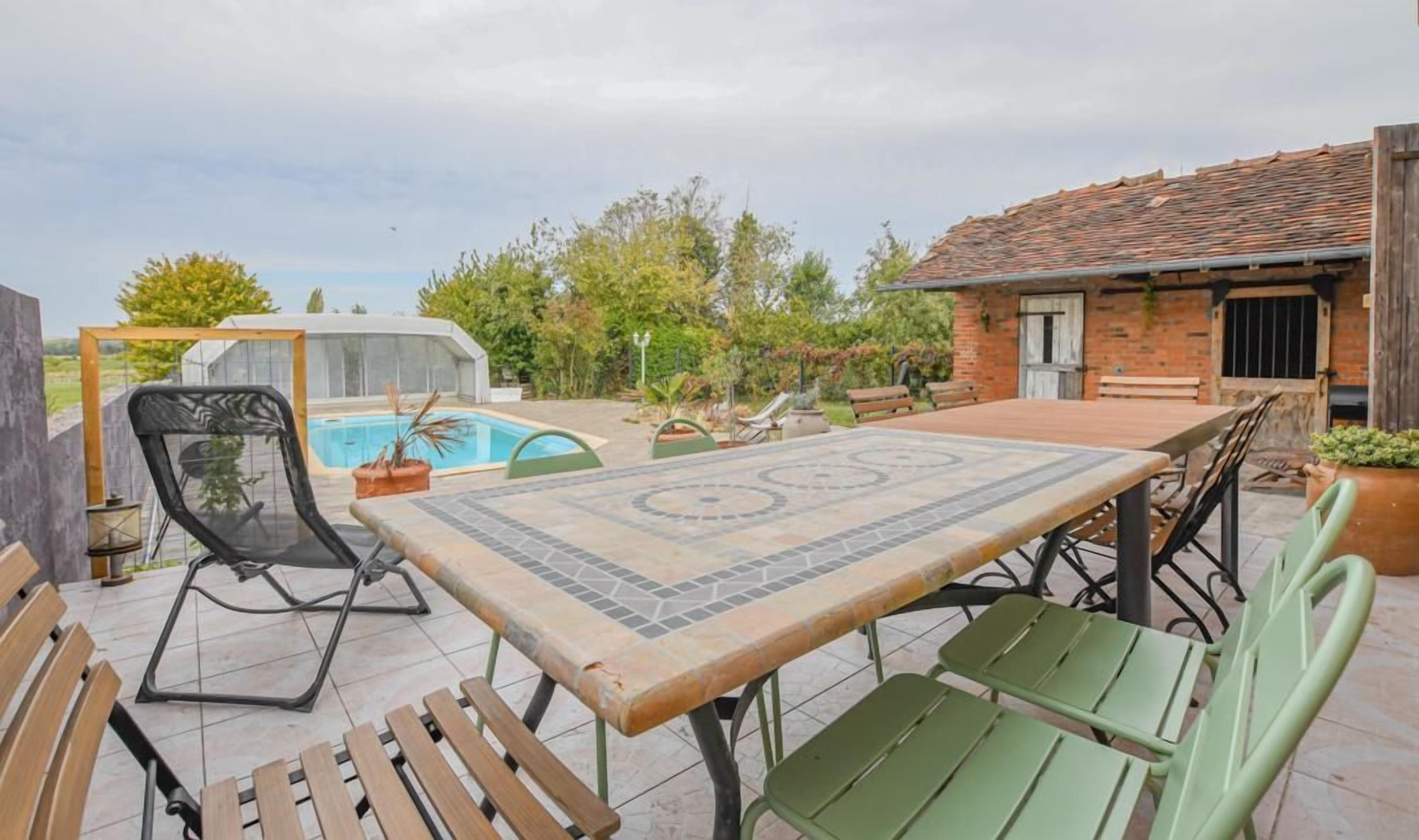 Eine Terrasse mit Pool, Whirlpool und Esstisch mit Stühlen.