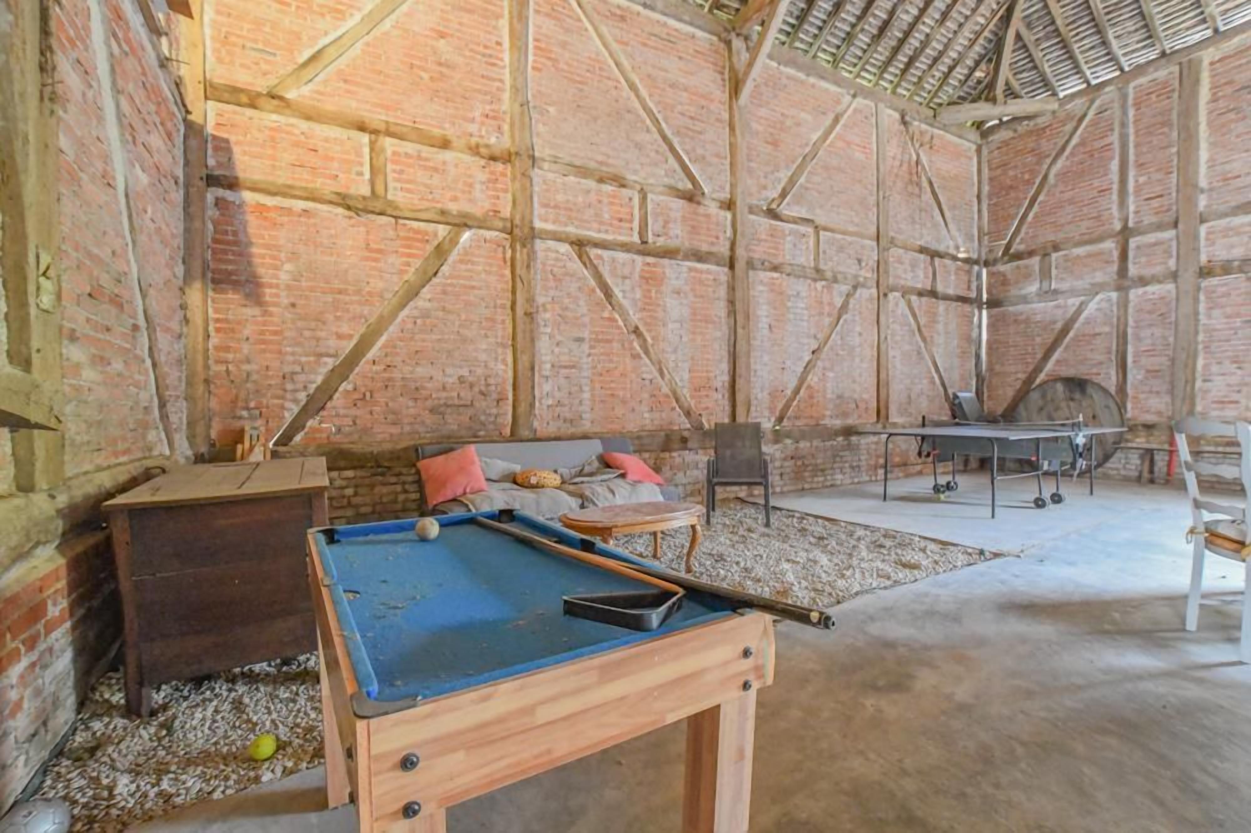 Una mesa de billar en una habitación con paredes de ladrillo y suelo de hormigón.