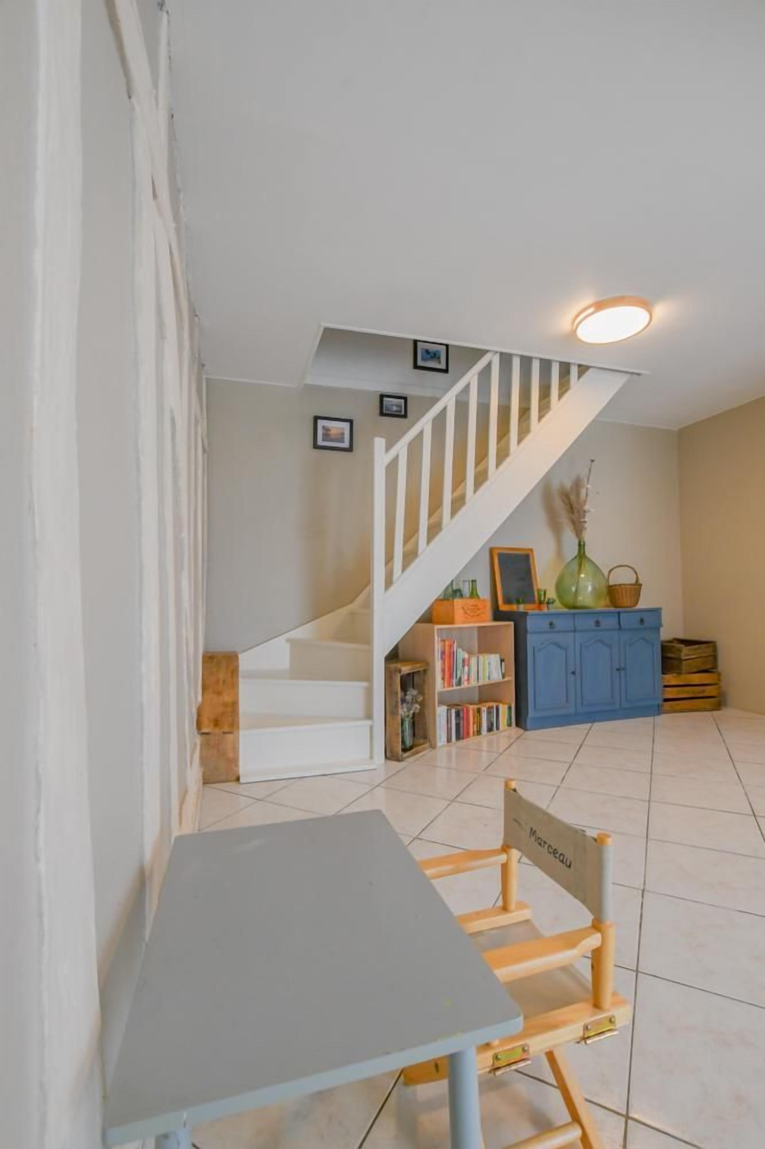 Ein Zimmer mit Treppe, Tisch, Stuhl und Bücherregal.