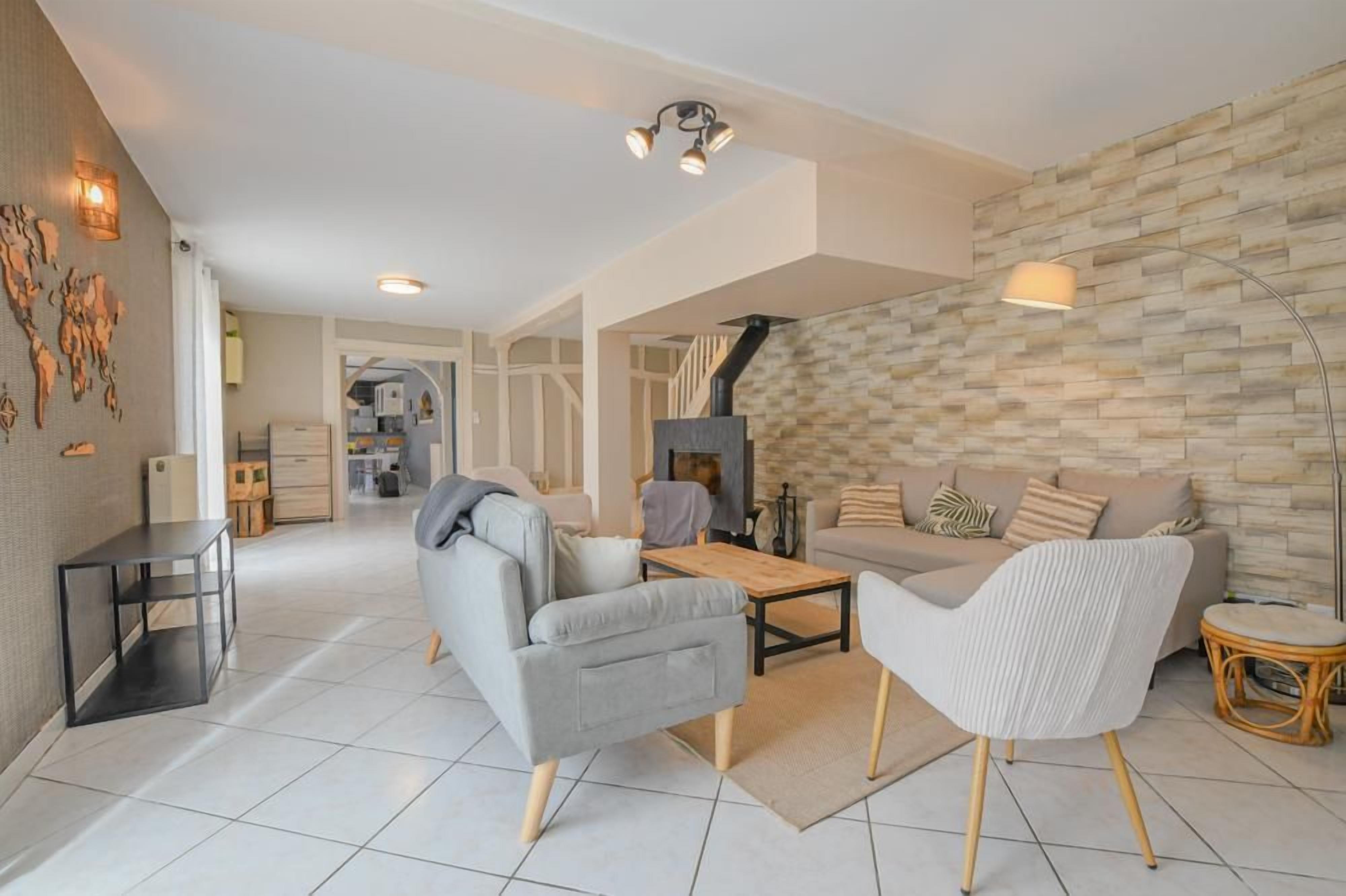 Un salon moderne avec un canapé, des fauteuils, une table basse et une cheminée.