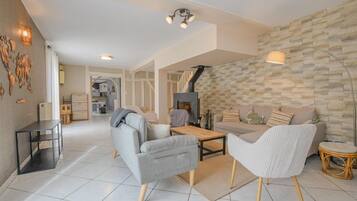 Un salon moderne avec un canapé, des fauteuils, une table basse et une cheminée.