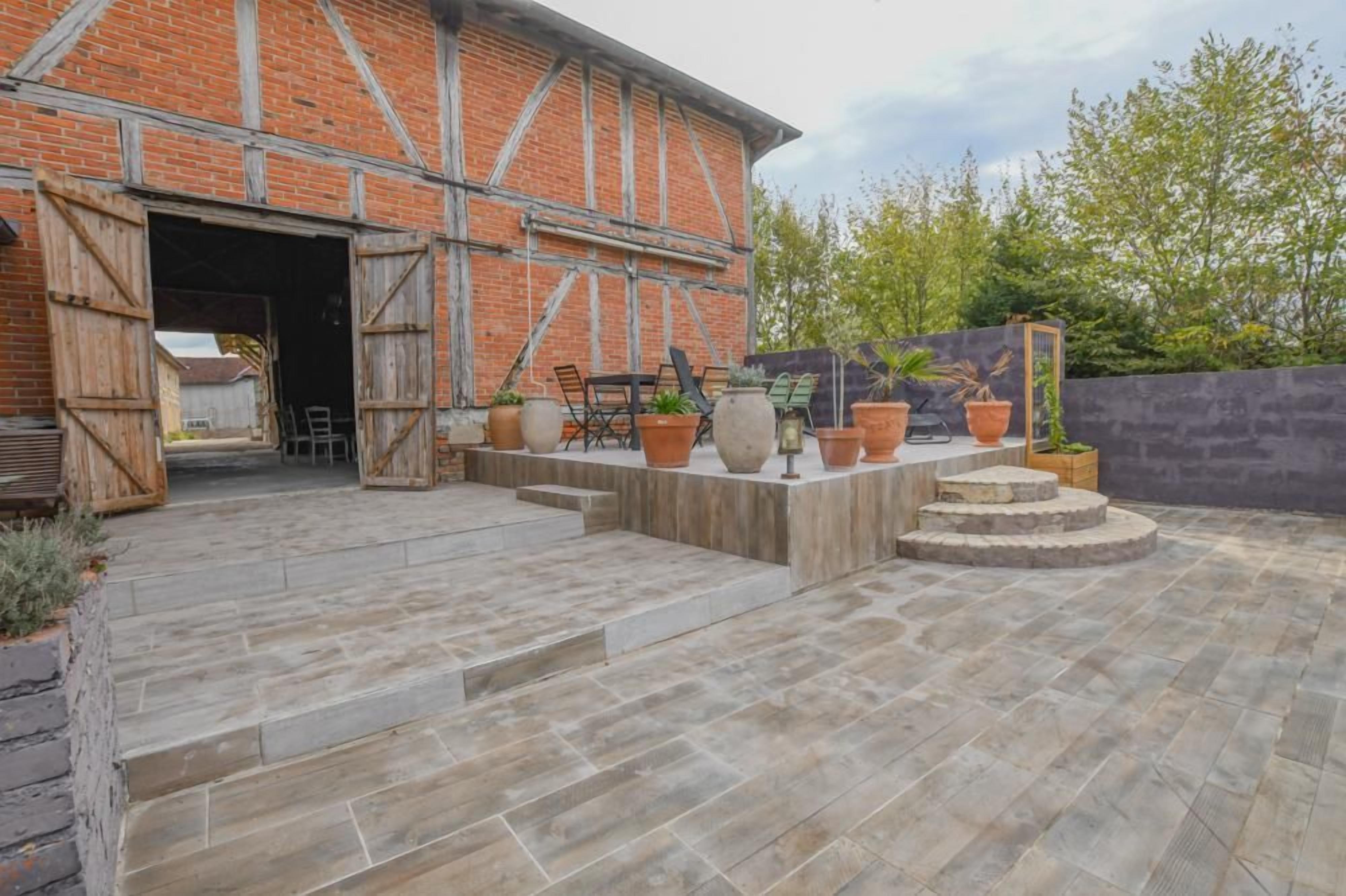 A brick building with a wooden door, outdoor seating, and potted plants.