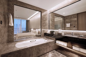 A modern bathroom with a large mirror, a bathtub, and a vanity with a black countertop. - ROSEDALE HOTEL SHENZHEN (Shenzhen)