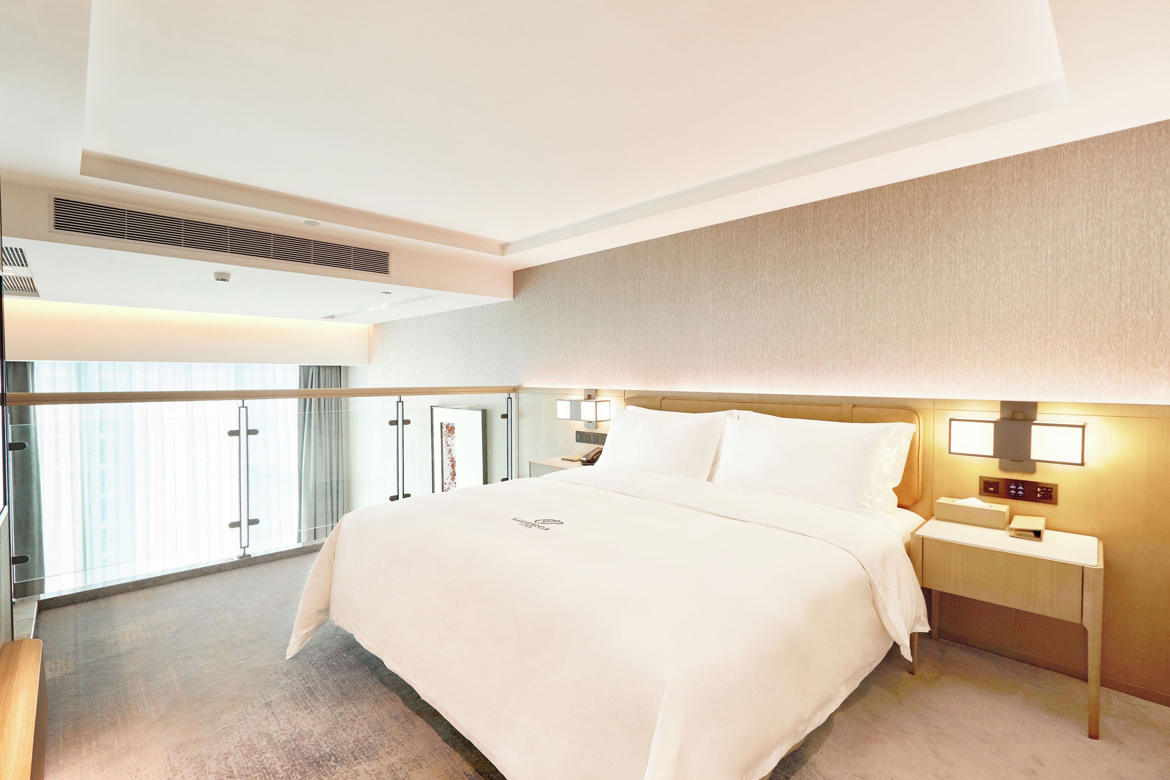 A hotel room with a large bed, bedside tables, a nightstand, a window with curtains, and a view of the outside.