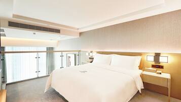 A hotel room with a large bed, bedside tables, a nightstand, a window with curtains, and a view of the outside.