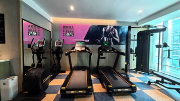 Un gimnasio con cintas de correr, una elíptica y una bicicleta estática.