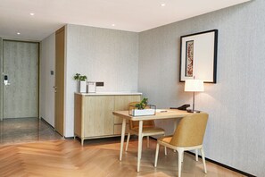 A modern room with a wooden desk, two chairs, a small table with a plant, a framed picture on the wall, and a lamp. - ROSEDALE HOTEL SHENZHEN (Shenzhen)