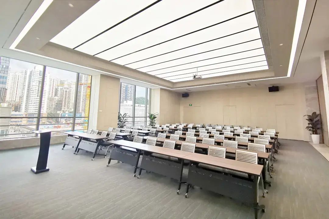 A conference room with a high ceiling, large windows, and a city view.