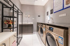 A laundry area with a washing machine, a sink, and a shelf with flowers. - ROSEDALE HOTEL SHENZHEN (Shenzhen)
