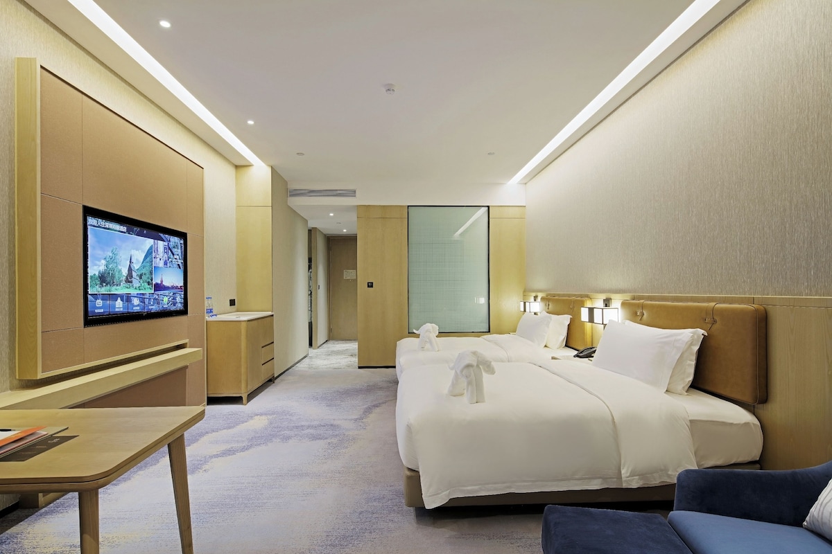 A hotel room with a bed, a desk, a television, and a mirror.
