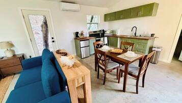 A compact living space with a dining area, kitchenette, and a sofa.