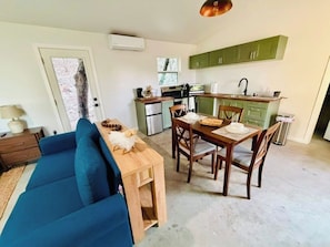 Un espacio habitable compacto con zona de comedor, kitchenette y sofá.
