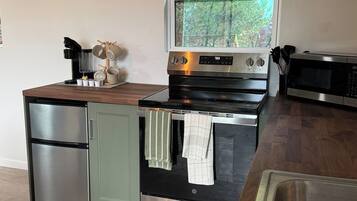 A compact kitchen with a built-in oven, a microwave, and a coffee maker.