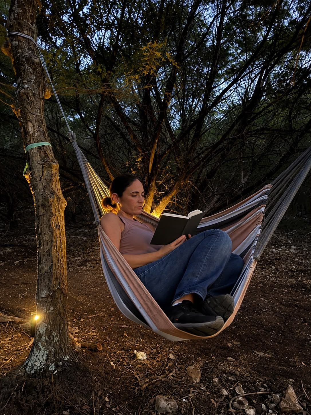 A hammock tied between trees in a wooded area.