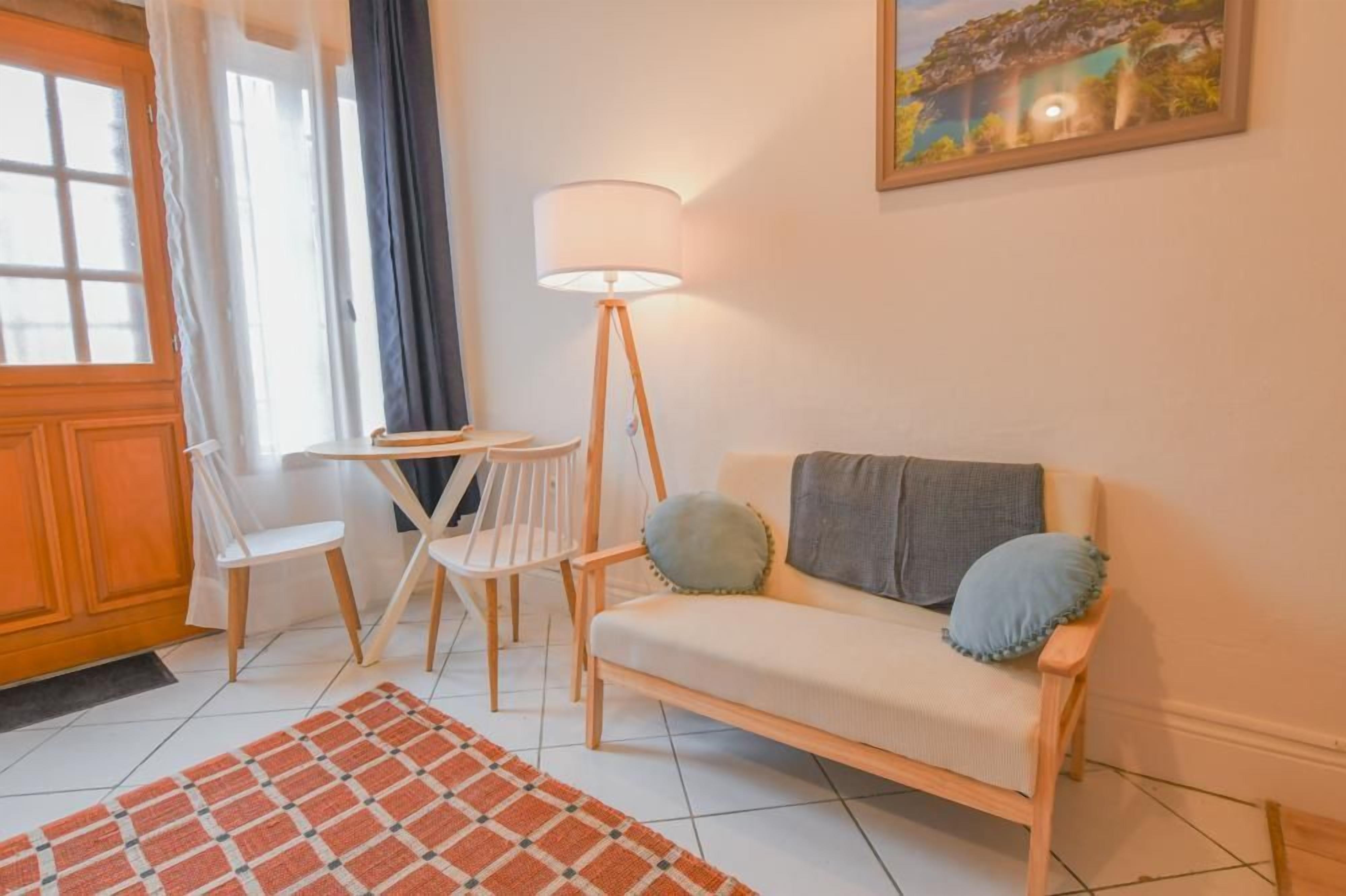 En hyggelig opholdsstue med sofa, stole, lampe og et tæppe.